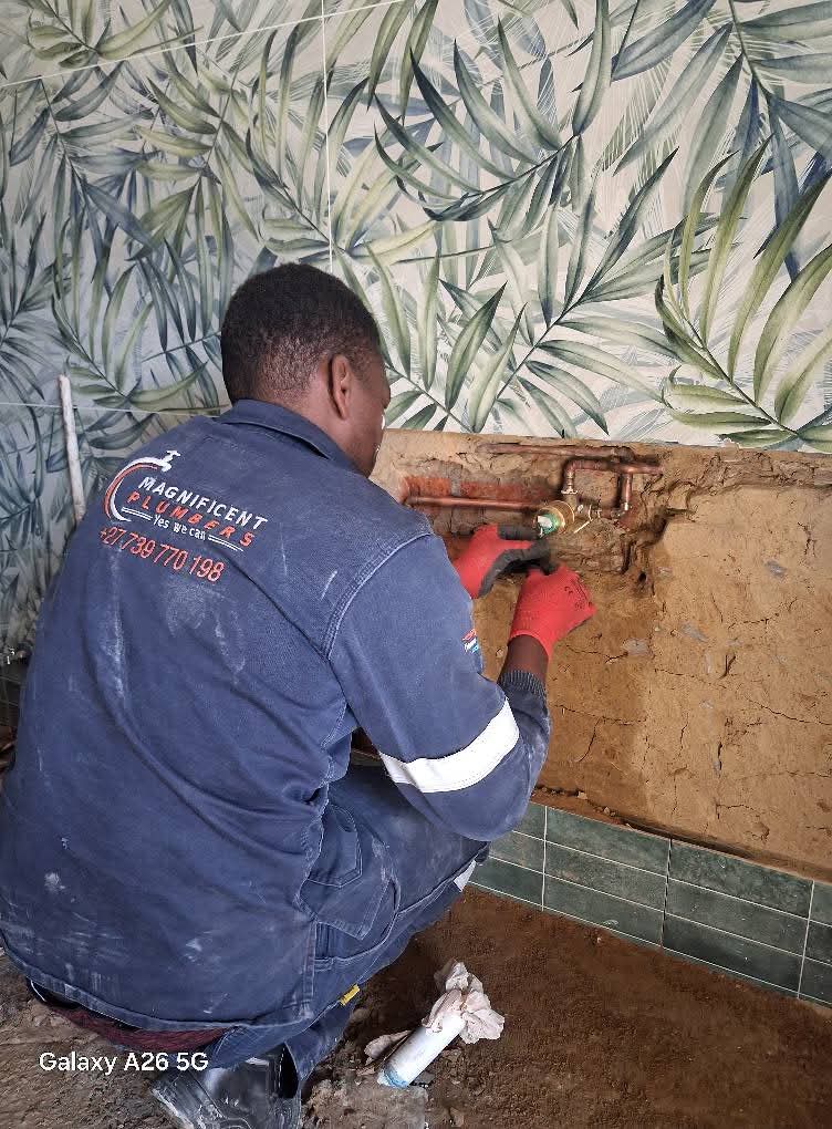 Plumber in blue uniform working on copper piping and a brass valve