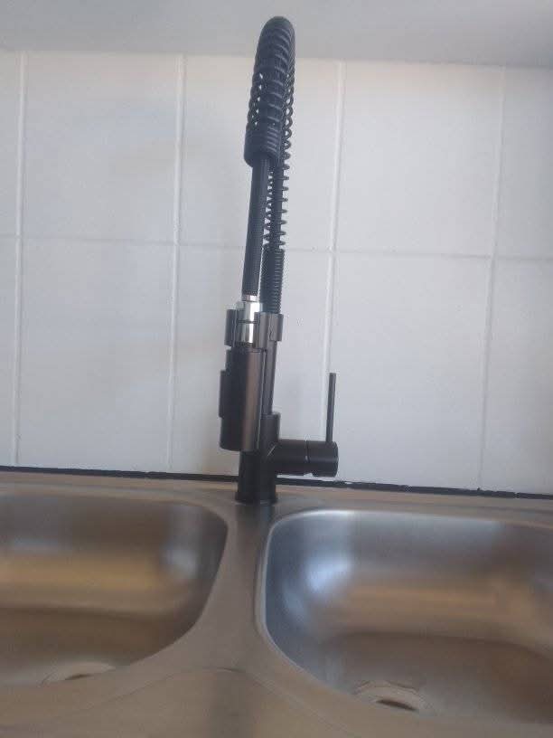 Modern matte-black high-arc kitchen faucet on a stainless steel sink