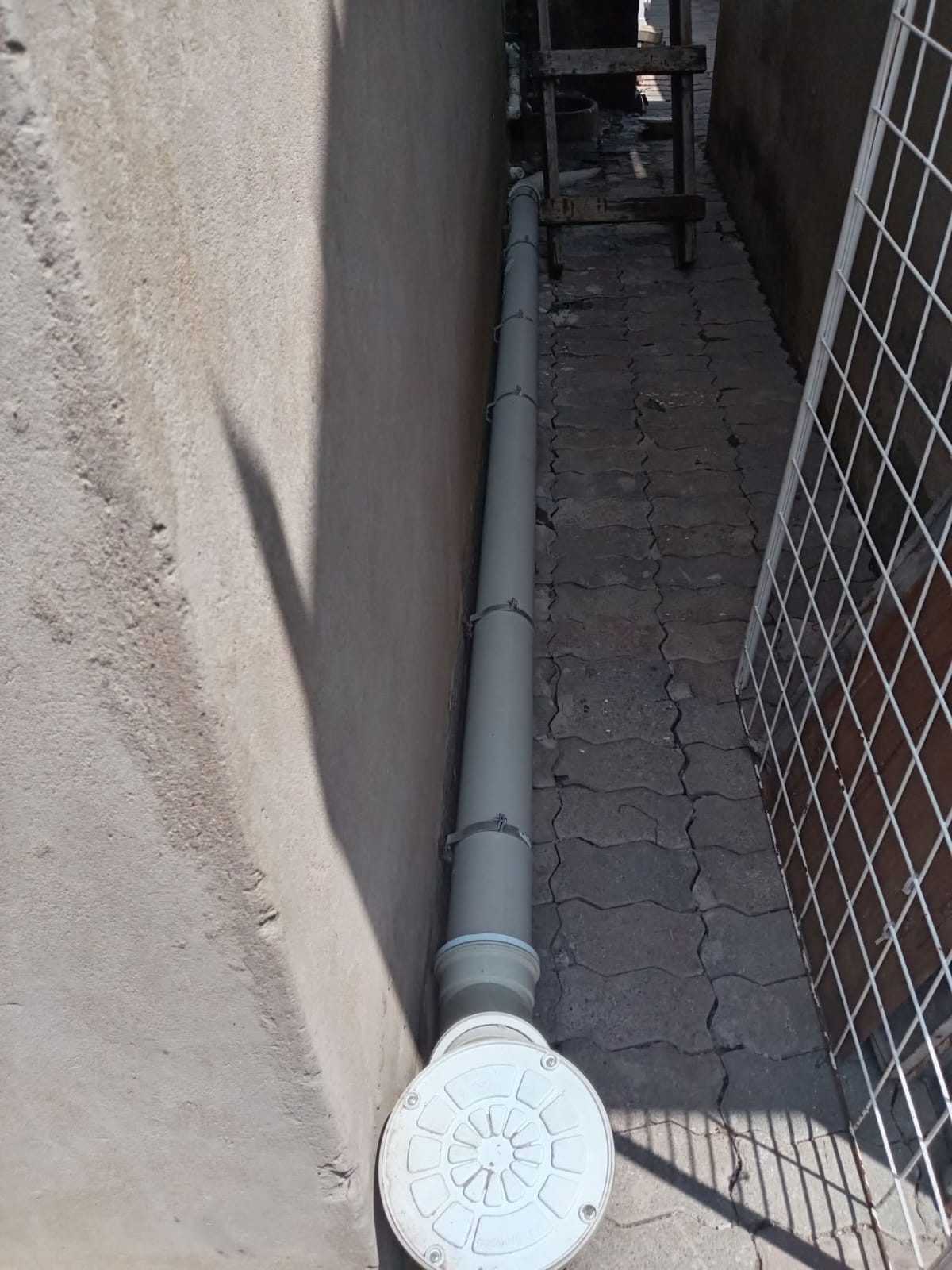 External drainage pipe installed along a concrete wall with a clean-out cover